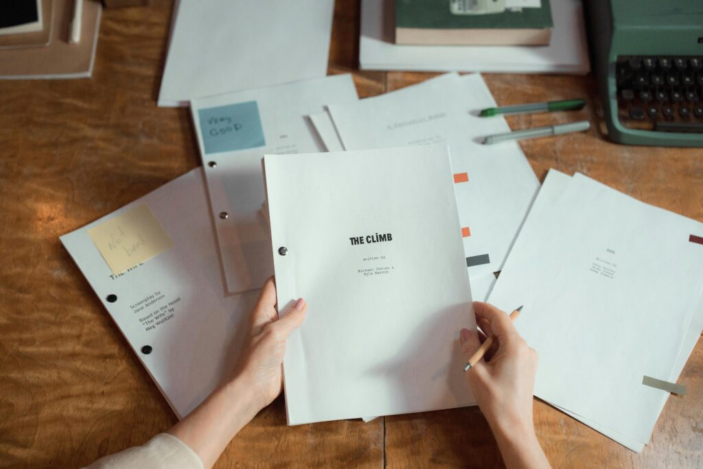 Close-up of hands holding script pages on a wooden desk with a typewriter.